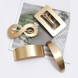 Close-up of four gold geometric hair clips including rectangle and infinity shapes