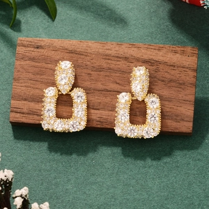 Detailed shot of gold-plated bow earrings with pavé zircons on a wooden stand