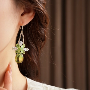 Detailed close-up of a floral zircon drop earring featuring green crystals on a model