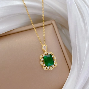 Gros plan du collier en or avec pendentif émeraude verte sur un tissu en soie blanche