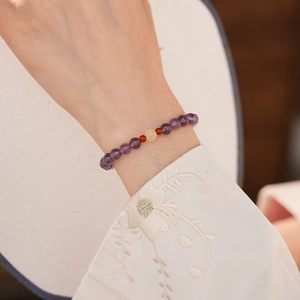 Detailed view of amethyst beaded bracelet with red agate and translucent center stone