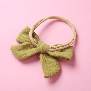 Detail of olive green muslin bow headband on soft nude elastic for babies and children