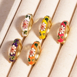 Makroaufnahme von 18K vergoldeten Creolen mit bunten Emaille-Blumenmustern