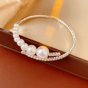 Detail of elegant pearl and rhinestone bracelet with gold silk background