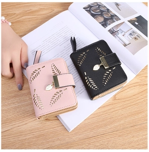 Detail of pink and black short wallets with hollow leaf patterns and metal pendants