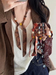 Bohemian floral fabric necklace with ethnic wooden beads worn on a brown blazer