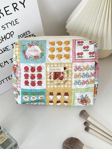 Detailed close-up of a quilted floral makeup bag with cute cartoon icons and zipper closure