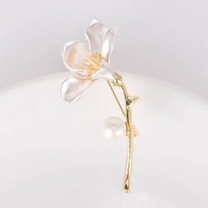Detailed view of lily brooch with pink enamel petals, gold stem, and elegant white pearl
