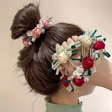 Detailed view of handmade satin rose hair ties in burgundy cream and matcha green