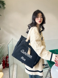 Close-up of black canvas tote bag with Summer Nice embroidery worn by model
