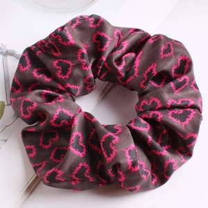 Detail of satin scrunchie with pink heart pattern on a dark fabric background