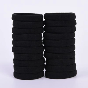 Detail view of two stacks of seamless black elastic hair ties made from soft knitted fabric
