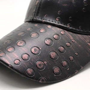 Detailed close-up of black PU leather baseball cap with vintage embossed metal texture