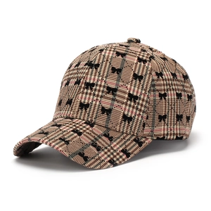 Close-up of brown plaid baseball cap with black bow embroidery and curved brim detail