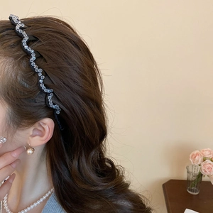 Detail view of wavy rhinestone headband worn by model with elegant pearl jewelry