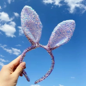 Sparkly sequin rabbit ear headband in purple and blue against a bright blue sky background