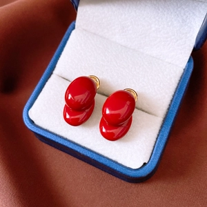 Macro view of 18K gold plated oval red enamel earrings inside a blue jewelry gift box