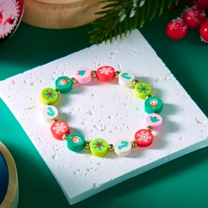 Weihnachtliches Perlenarmband mit Weihnachtsmann-Anhängern auf festlichem grünem Grund