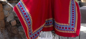 Gros plan du poncho ethnique rouge avec motif de cœur tissé et de longs glands noirs