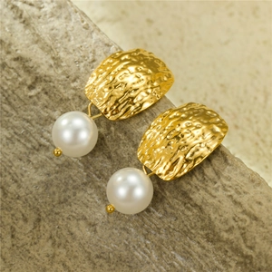 Square hammered gold earrings with freshwater pearls on a natural stone background