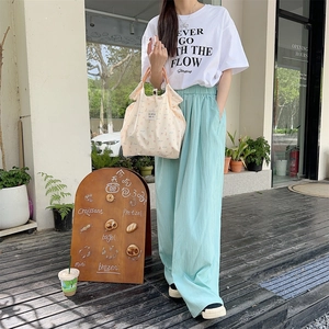 Floral canvas tote bag shown in an outdoor cafe setting with a stylish casual outfit