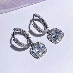 Macro shot of silver drop earrings featuring square cushion cut stones and halo pavé detail