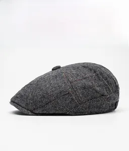 Side view of dark grey herringbone wool newsboy cap with orange pane pattern detail