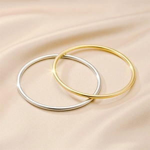 Makrodetailansicht von polierten minimalistischen Armreifen aus Titanstahl in Gold und Silber