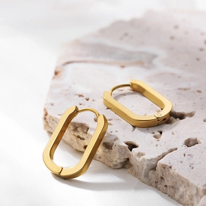 Macro shot of polished gold oval hoop earrings on stone display with latch back closure
