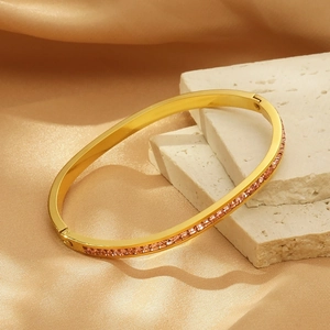 Détail du bracelet en acier titane doré avec zircons roses sur blocs de marbre