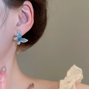 Gros plan d'une élégante boucle d'oreille papillon bleue et blanche avec des zircons