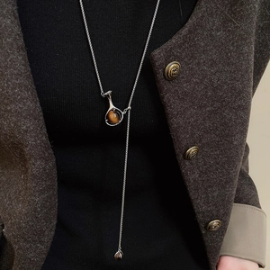 Detail of Y-shaped silver long necklace featuring a round tiger eye stone pendant