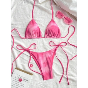 Flat lay of pink tie-dye bikini set with lace-up straps and stylish beach accessories