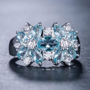 Dettaglio macro di un anello a fiore con gemme marquise blu e pavé di zirconi bianchi