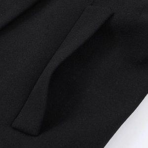 Gros plan sur la poche diagonale et la texture du tissu en laine du manteau noir