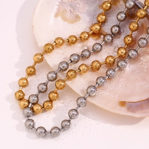 Détail de colliers de perles dorées et argentées sur un coquillage avec des gouttes d'eau