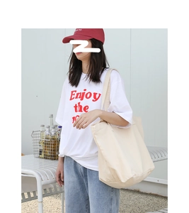 Detailed close-up of a large beige canvas tote bag shown in natural outdoor light