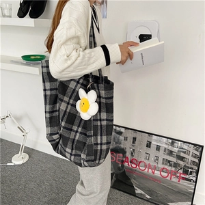 Model carrying a large plaid wool tote bag in a minimalist lifestyle setting