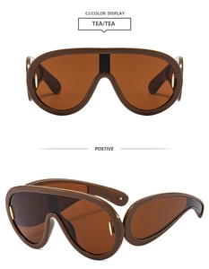 Detail view of tea-colored Y2K oversized sunglasses with golden oval metal accents