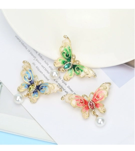 Detail of colorful butterfly brooches with enamel wings and hanging white pearls