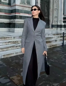 Fashionable long gray wool coat with waist tie and lapel shown in elegant city street scene