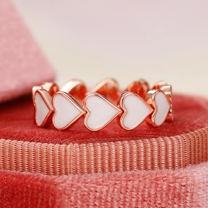 Détail macro de la bague coeur en or rose et émail blanc dans un écrin en velours