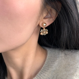 Elegant gold flower earrings with pearls and crystals worn on model in a side view