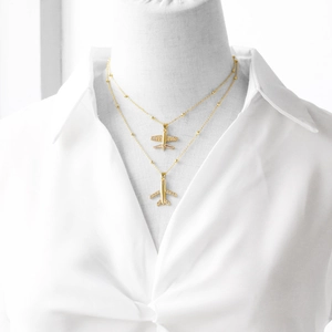 Detailed close-up of double-layered gold plane pendant necklace with CZ-inlaid wings