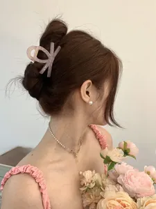 Close-up of elegant pink bow hair clip with matching pearl necklace on a female model