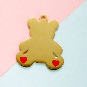 Detail of a gold bear pendant featuring red heart accents and a top hanging loop