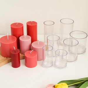 Clear acrylic cylinder candle molds set with colorful finished wax candles on white background