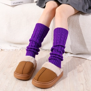 Detailed knit texture of purple cable-knit leg warmers and brown plush slippers