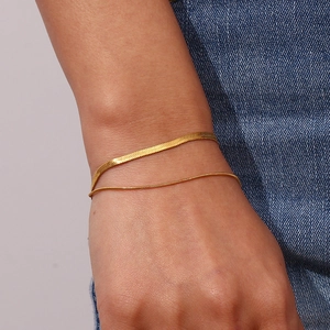 Detail of double-layer gold snake chain and herringbone bracelet set on wrist