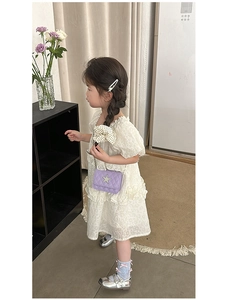 Child model wearing a purple quilted star crossbody bag with silver chain strap
